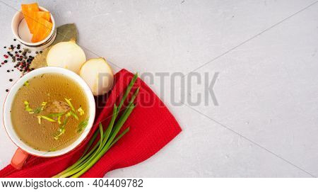Hot Homemade Beef Bone Broth With Collagen And Amino Acids In Red Bowl With Red Napkin And Green Oni