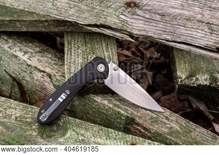 Knife With Clip In Folded Position. Knife On Wooden Sticks.