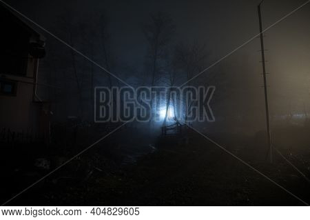 Night Street Country Road With Buildings And Fences Covered In Fog Lamp . Or Mysterious Night In Aze