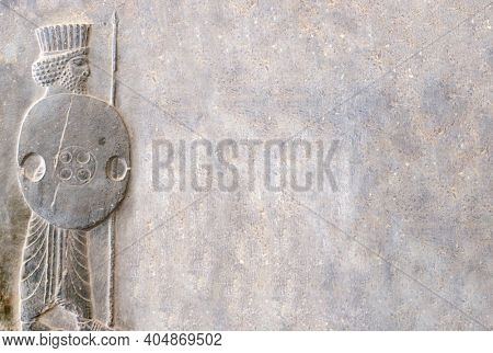 Ancient wall with bas-relief - assyrian warrior with spear and shield, Persepolis, Iran. Horizontal background with embossed image persian bearded man. Mock up template. Copy space for text