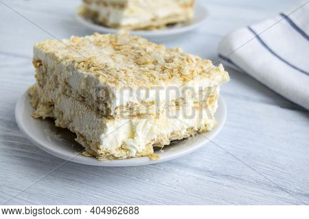 A Piece Of Cake Is On A White Plate. Napoleon Cake Consists Of Ice Cream, Layered Dough And Biscuit 