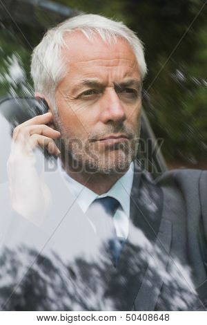 Serious businessman on the phone driving expensive car