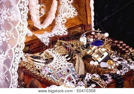 Old wooden open chest with golden jewelry and laces