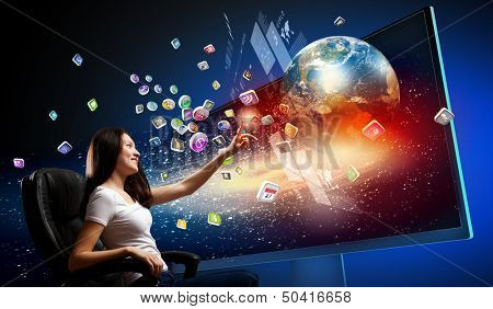 Young woman in armchair pushing icon on media screen. Elements of this image are furnished by NASA