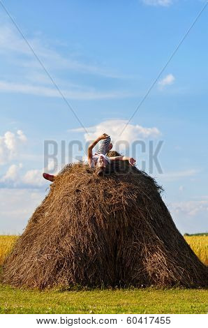 Little Cheerful Girl On Hayrick In Wheat Field.