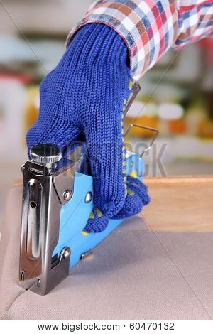 Fastening fabric and wooden box using construction stapler on bright background