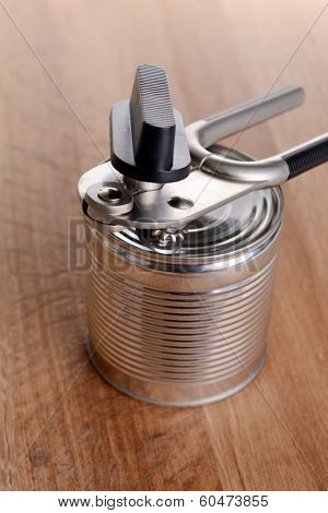 Can piercer with canned on wooden background