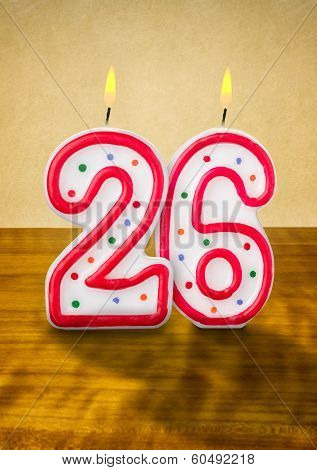 Burning birthday candles number 26 on a wooden background