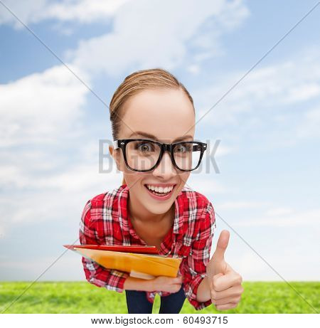 education and gesture concept - smiling student in black eyeglasses with folders showing thumbs up