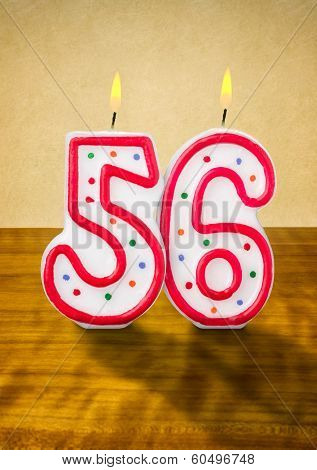 Burning birthday candles number 56 on a wooden background
