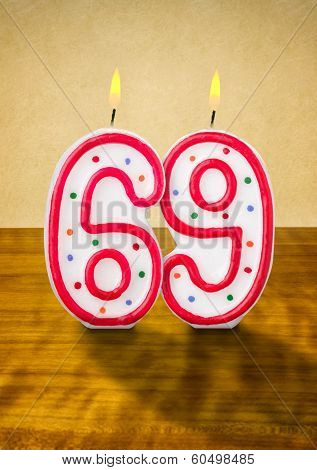 Burning birthday candles number 69 on a wooden background