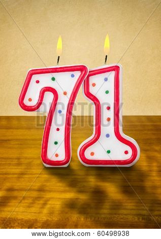 Burning birthday candles number 71 on a wooden background