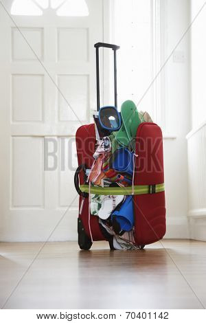 Overstuffed suitcase in hallway