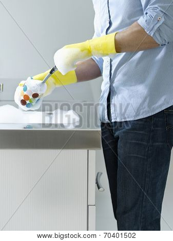 Side view of a midsection man doing washing up at kitchen sink