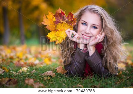 woman lying on autumn leaves, outdoor portrait
