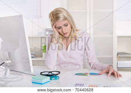 Depressed And Frustrated Young Businesswoman Sitting At Desk With Migraine.