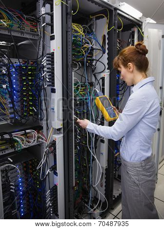 Technician using digital cable analyzer on server in large data center