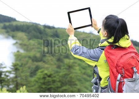 woman hiker in emei mountain taking photo with digital tablet