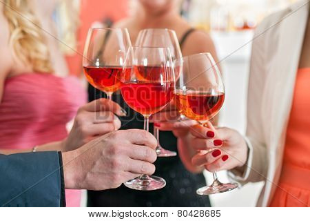 Friends Tossing Glasses Of Red Wine