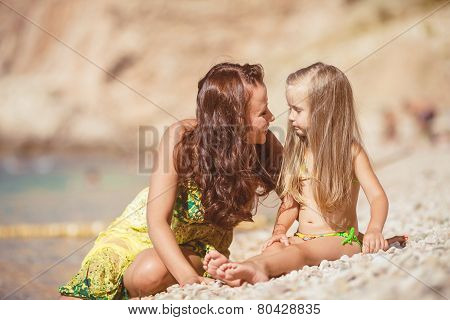 Happy mom and her adorable little daughter during summer vacation on the beach