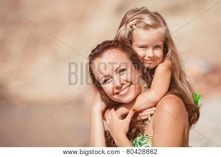 Happy mom and her adorable little daughter during summer vacation on the beach