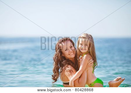Happy mom and her adorable little daughter during summer vacation on the beach