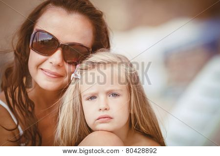 Happy mom and her adorable little daughter during summer vacation on the beach