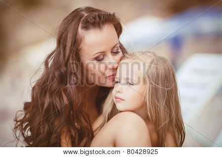 Happy mom and her adorable little daughter during summer vacation on the beach