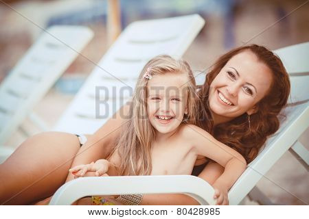 Happy mom and her adorable little daughter during summer vacation on the beach