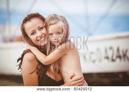 Happy mom and her adorable little daughter during summer vacation on the beach
