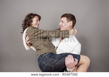 Happy Caucasian Couple Standing Embraced Together. Against Gray Background