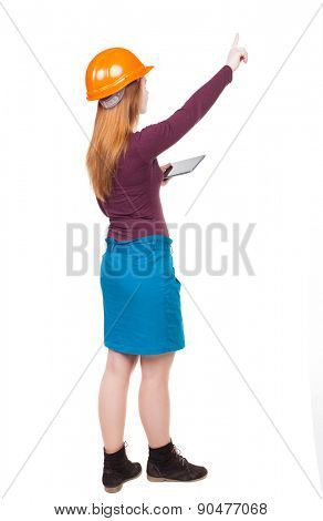 Backview of business woman in construction helmet with  tablet pc pointing. Standing young girl. Rear view people collection.  backside view of person. Engineer scorekeeper hand shows the work front.