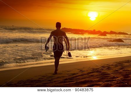Surfer walking with board along the beach