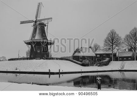 Historical Windmill In Snow Next To Water