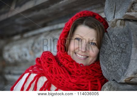The Russian woman in a shawl warms hands near an izba