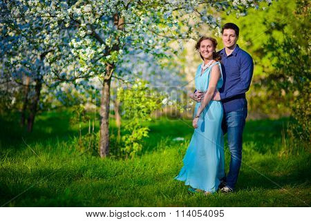 Young beautiful couple in love among apple trees