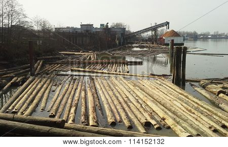 Log booms and a lumber mill along a river