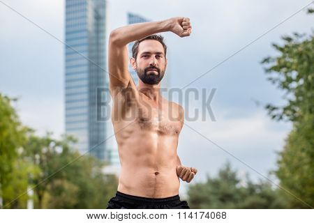 Mann practicing qigong outdoors, office building in background
