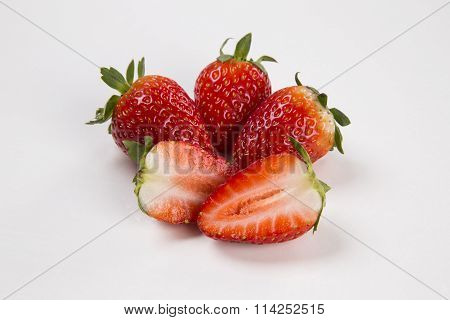 A Strawberry Cut In A Half In Front Of Three Entire Strawberries