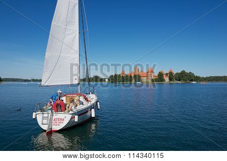 People enjoy boat trip at Galve lake with the Trakai castle at the background in Trakai.