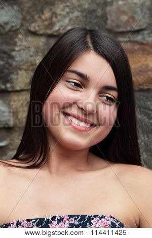 Young smiling teenage european girl with dark hair in a strapless dress.