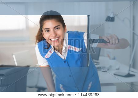 Smiling Female Worker Cleaning Glass Window With Squeegee