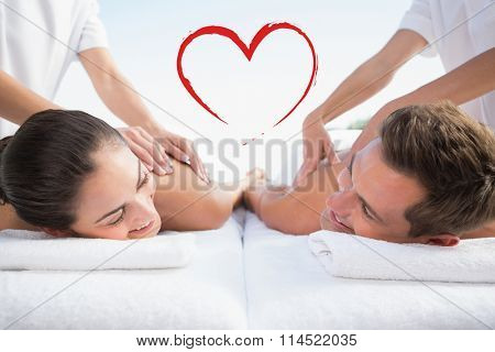 Peaceful couple enjoying couples massage poolside against heart