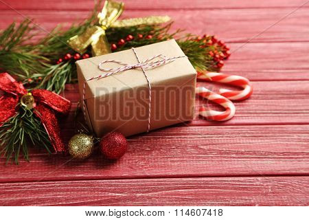 Christmax Tree Branch With Baubles, Candies And Gift Box On Red Wooden Table