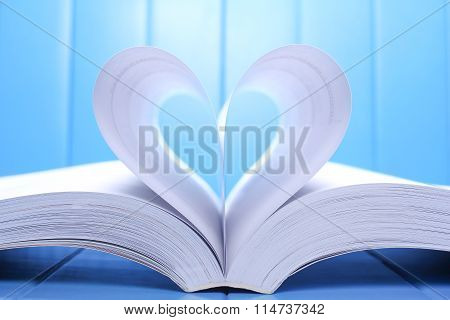 Open Book Pages Into A Heart Shape.on Blue Background.