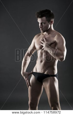 Handsome Muscular Bodybuilder Posing On Gray Background. Low Key Studio Shot