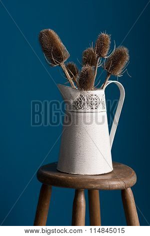 Close Up View Of Old Vase With Thistles On Stool