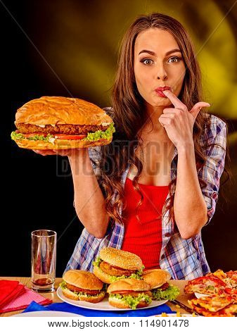 Girl taste fastfood big hamburger and pizza .