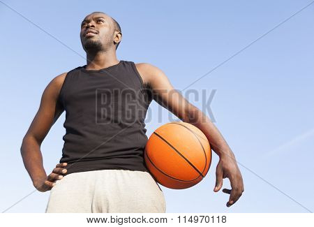 Afroamerican man street basket player holding a basketball against blue sky