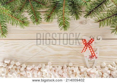 Christmas theme. Greeting card with place for Your text. White wooden background and marshmallows instead of snow. Reindeer Prancer.